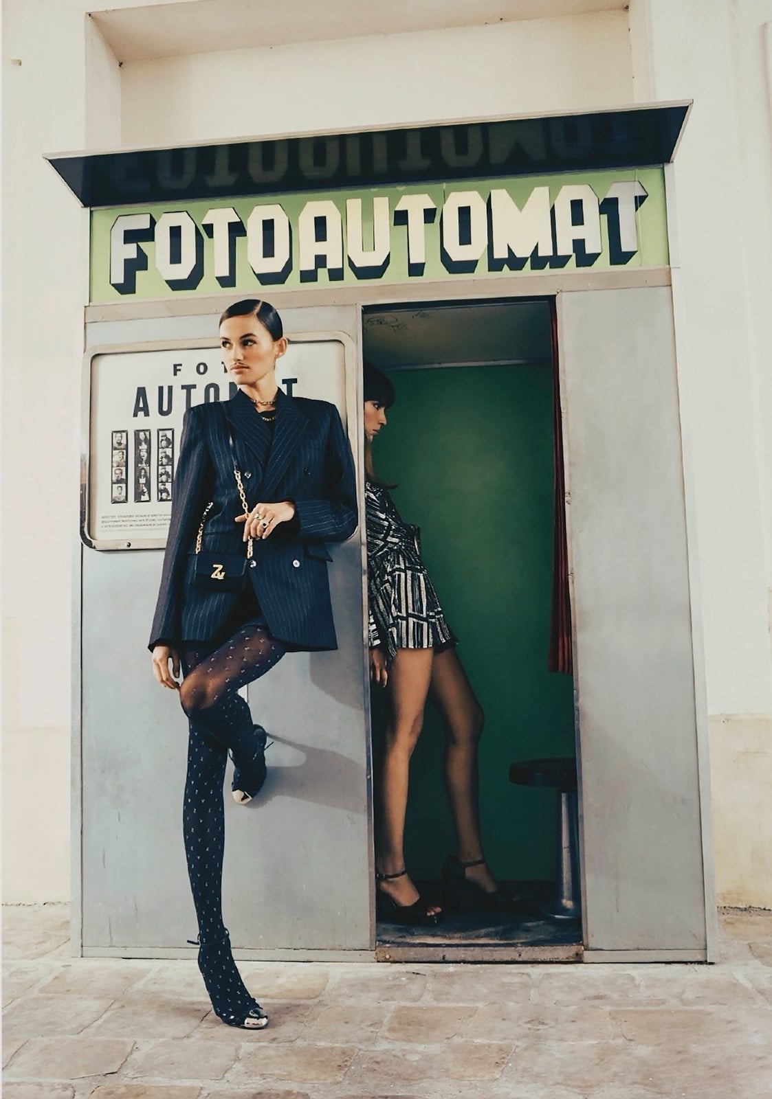 fashion models photographed in front of a vintage metal photo booth