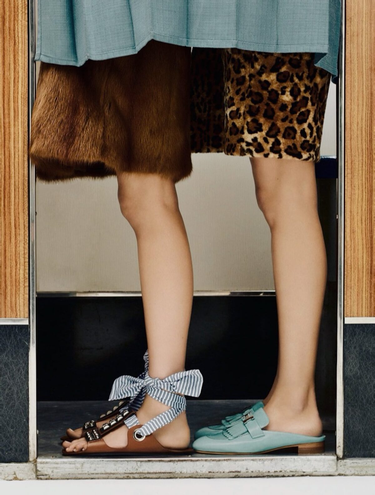 jambes de femmes en sandales et fourrure debout dans un photomaton