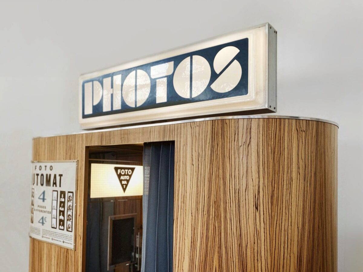 round silver photo booth with a backlit sign 