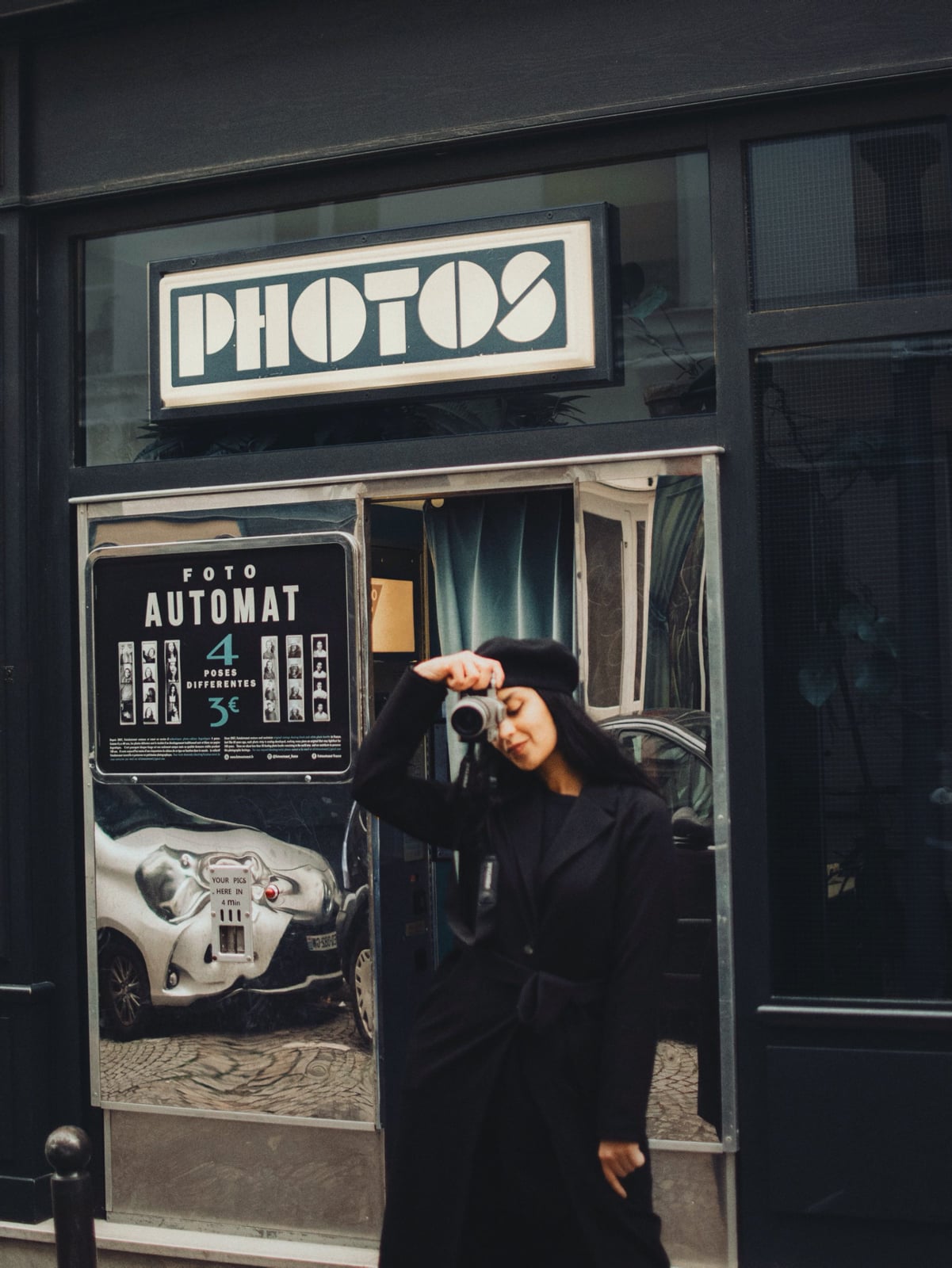 woman holding a camera in front of a metal photo booth