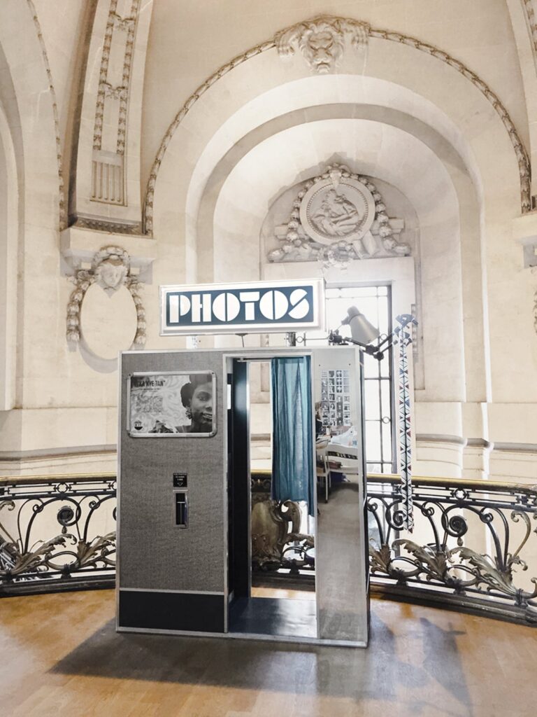 photomaton posé sur un parquet dans une salle en marbre sculpté