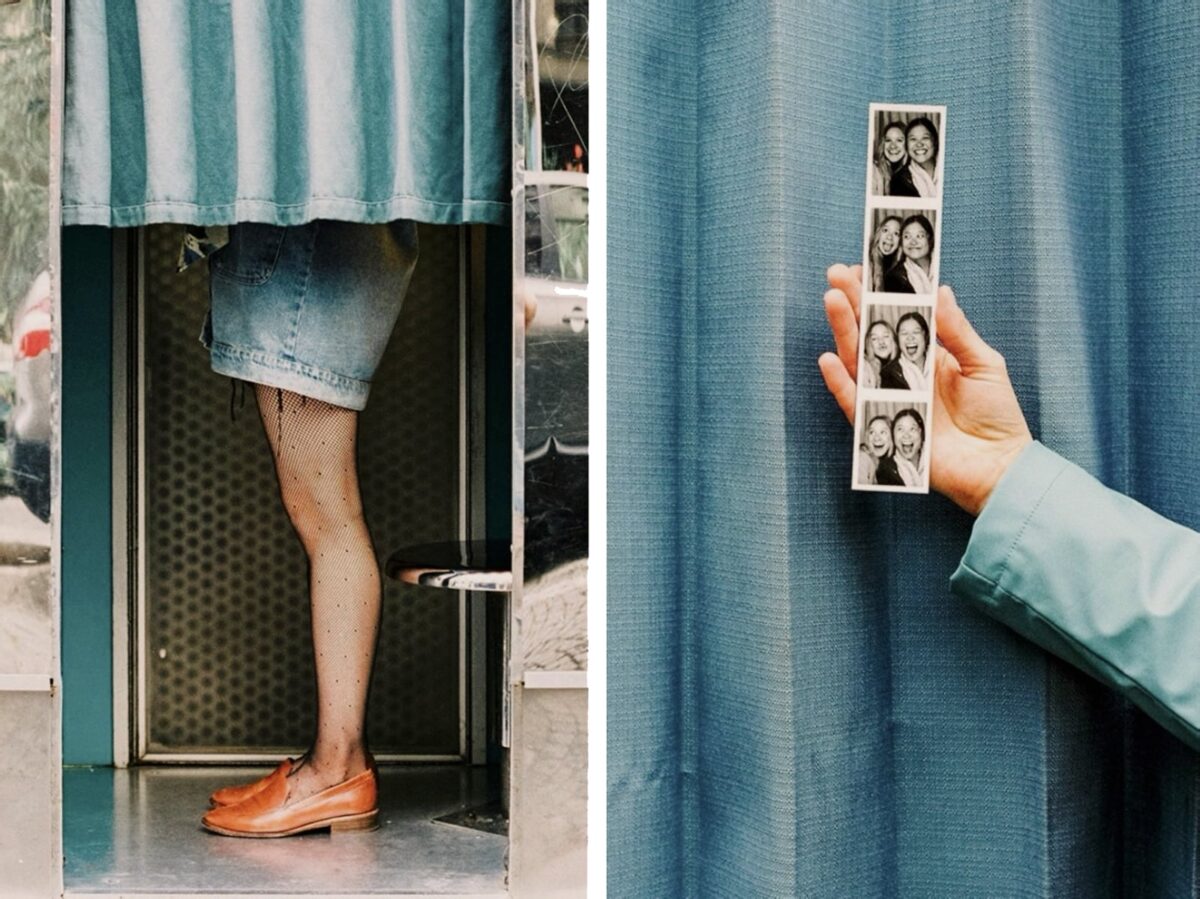 femme debout dans un photomaton et main tenant un portrait photo devant un rideau bleu